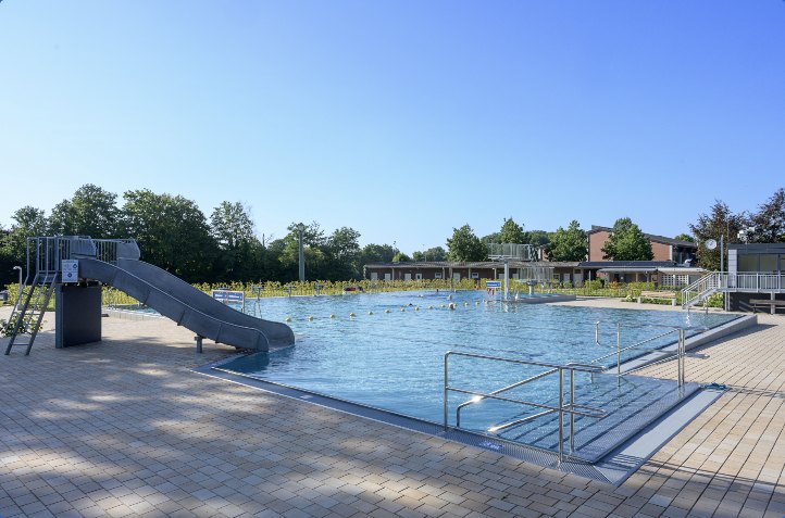 Freibad Nortrup: Rutsche am Beckenrand, dahinter das große Schwimmbecken und das Betriebsgebäude